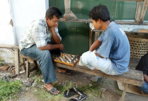 Zwei junge Maenner spielen am Strassenrand Schach