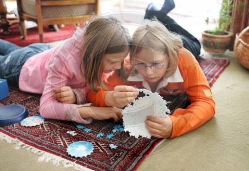 Zwei Maedchen spielen mit einem Puzzle