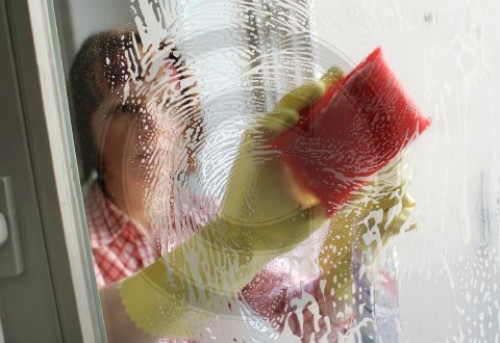 Frau beim Fenster putzen