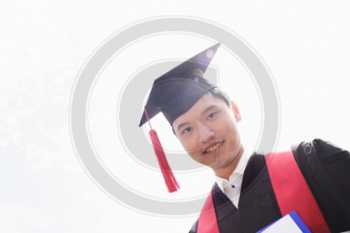 Asiatischer Jurastudent  als Studienabsolvent in Talar