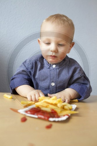 Ein kleiner Junge isst Pommes Frites
