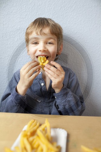 Ein Junge isst Pommes Frites