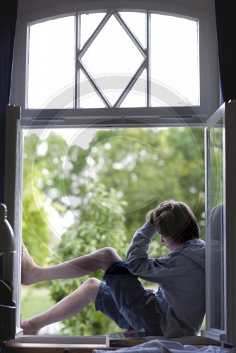 Jugendlicher liest im Fenster