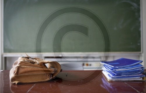 Klassenzimmer mit Aktentasche und Heftestapel