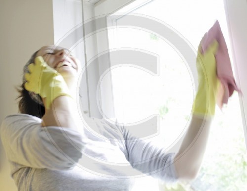Hausfrau putzt Fenster und telefoniert