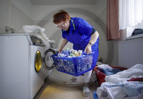 Arbeiterin belaedt Waschmaschine