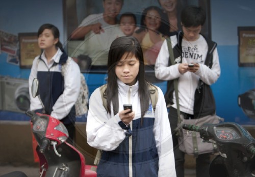 Junge Vietnamesin in Schuluniform mit ihrem Handy| Young Vietnamese woman in school uniform with her cell phone