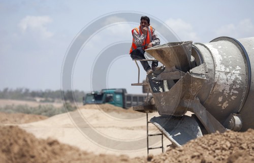 A worker at a cement mixer at the construction site of a sludge drying facility in East Burei / Palestinian Territories. 14.06.2011