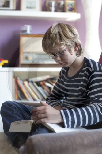 Zehnjaehriger Junge liest einen Schmoeker|Ten year old boy reading