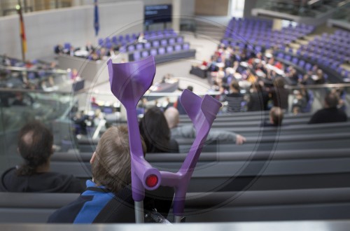 Junge mit Kruecken verfolgt eine Debatte im Deutschen Bundestag