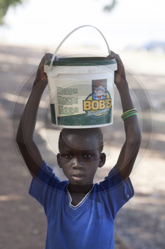 Junge in Afrika traegt einen Eimer auf dem Kopf