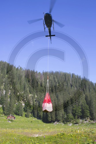 Hubschrauber versorgt eine Almhuette mit Lebensmitteln