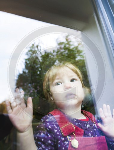 Kind hinter einer Fensterscheibe