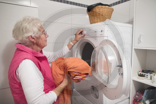 Seniorin belaedt eine Waschmaschine