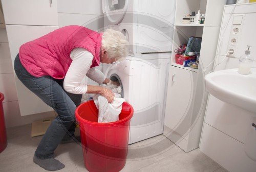 Seniorin belaedt eine Waschmaschine