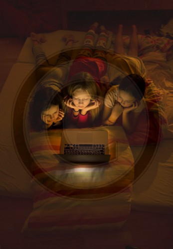 Maedchen lesen im Bett in einem Laptop