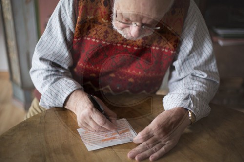 Rentner beim Ausfuellen eines Formulars
