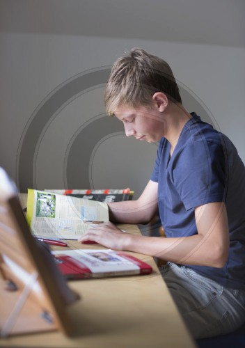 Jugendlicher sitzt konzentriert am Schreibtisch