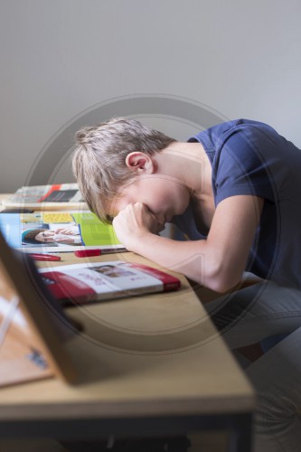 Jugendlicher sitzt unkonzentriert am Schreibtisch