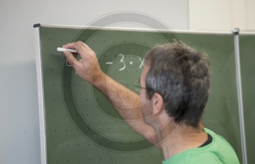 Lehrer schreibt an eine Tafel