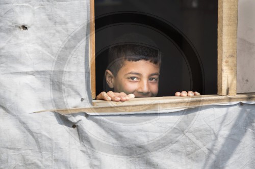 Junge, syrischer Fluechtling am Fenster seines Zeltes