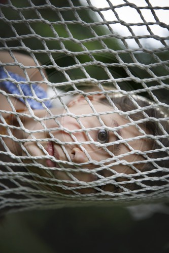 Kind guckt durch ein Netzt