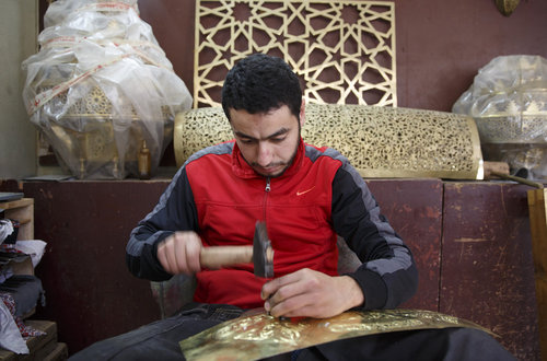 Junger Mann beim Beschlagen von Kupferblech im Zentrum fuer Kunsthandwerk in Meknes