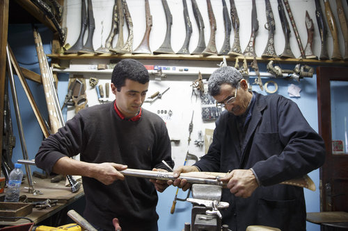 Vater und Sohn bei Intarsienarbeiten an einem Gewehr im Zentrum fuer Kunsthandwerk in Meknes