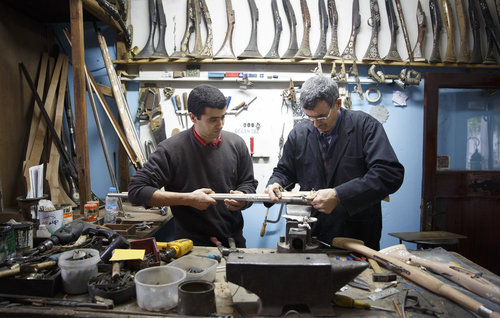Vater und Sohn bei Intarsienarbeiten an einem Gewehr im Zentrum fuer Kunsthandwerk in Meknes