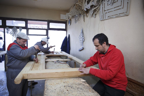 Maenner bei Holzschnitzarbeiten an einer Tuer im Zentrum fuer Kunsthandwerk in Meknes