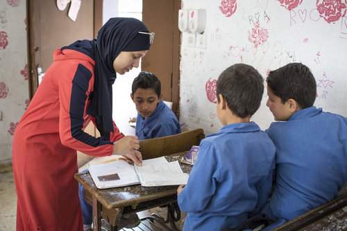 Lehrerin und syrische Schueler waehrend es Unterrichts an einer Doppelschichtschule in Amman