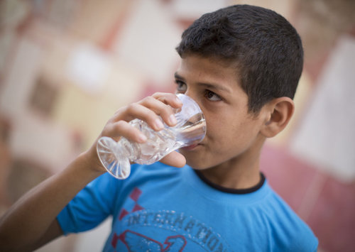 Durstiger Junge trink Wasser aus einem Glas
