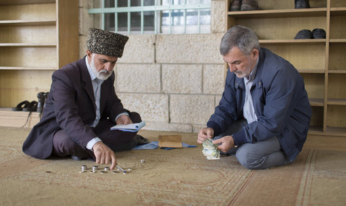 Muslime zaehlen die Kollekte nach einem Freitagsgebet in einer Moschee