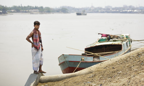 Bangladeschi neben seinem Boot an einem Fluss in Khulna