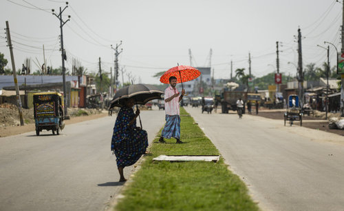 Fussgaenger ueberqueren eine Strasse in Bangladesch