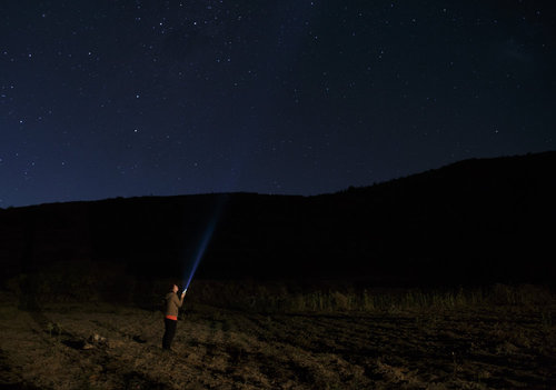 Frau mit Taschenlampe unter der Milchstrasse in den Anden