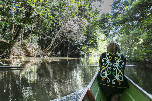 Einwohner Borneos in traditioneller Kleidung der Gemeinde Tephian Buah in einem Boot im Urwald,