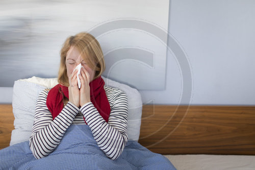 Frau liegt krank im Bett