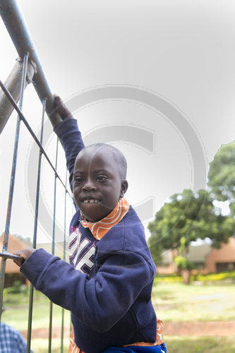 Junge mit Trisomie 21 an einem Klettergeruest in Malawi
