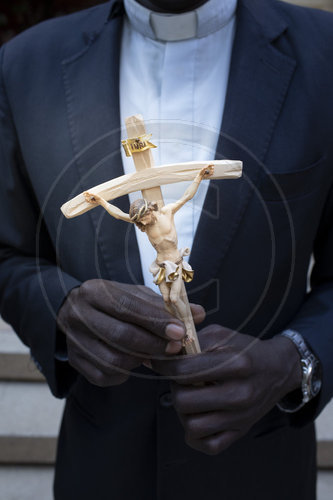 Kruzifix in den Haenden eines schwarzen Priesters