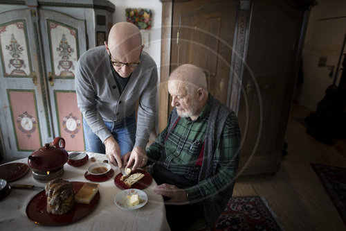 Mann hilft dem alten Vater ein Brot zu schmieren
