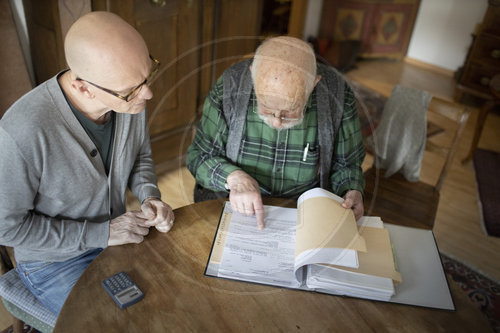 Aelterer Man bekommt Hilfe beim Sortieren seiner Unterlagen