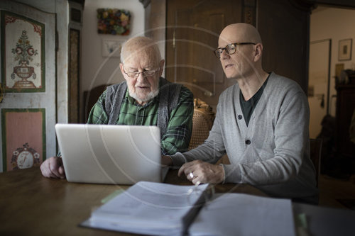 Vater und Sohn sitzen vor einem Laptop.