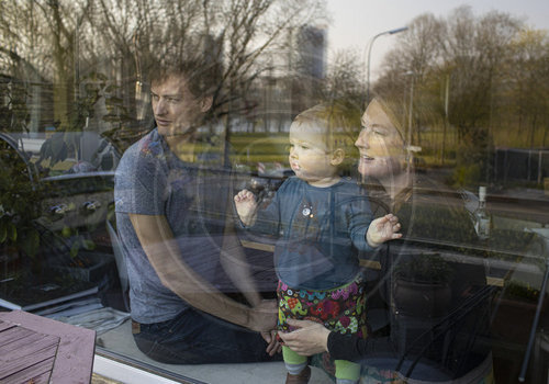 Eltern mit Kind hinter einem Fenster