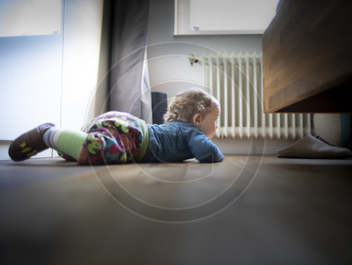 Kind sucht sein Spielzeug unter einem Bett