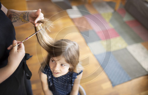 Mutter schneidet der Tochter die Haare
