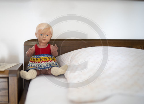 Alte Puppe sitzt auf einem Bett