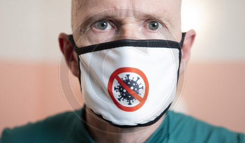 Mann mit Maske, auf der das Corona-Virus abgebildet ist.