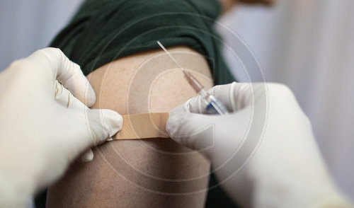 Thema: Impfung. Arzt klebt ein Pflaster auf die Einstichstelle
