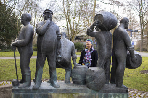 Thema: Frau betrachtet einen Brunnen mit Figuren zum Thema Bierbrauen